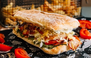ПАНИНИ - знаменитый итальянский сендвич. Подается на булочке чиабата, с беконом, сочной курицей, мягким сыром, свежими овощами и орехово-кунжутным соусом.